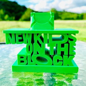 May include: A green 3D printed sculpture of the words "New Kids on the Block".
