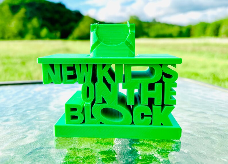 May include: A green 3D printed sculpture of the words "New Kids on the Block".
