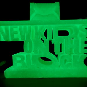 May include: A green glow-in-the-dark plastic phone stand with the words "NEW KIDS ON THE BLOCK" in raised letters.