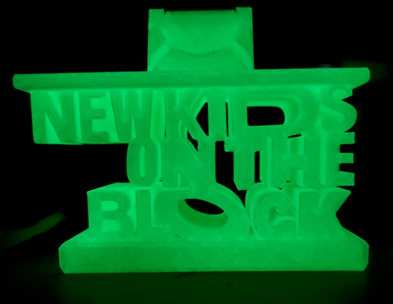 May include: A green glow-in-the-dark plastic phone stand with the words "NEW KIDS ON THE BLOCK" in raised letters.