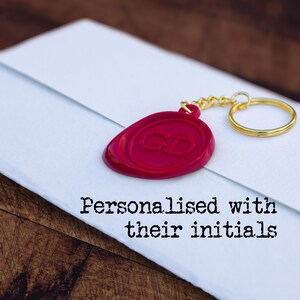 Red wax seal-style keyring on a folded task, with text 'Personalised with their initials'