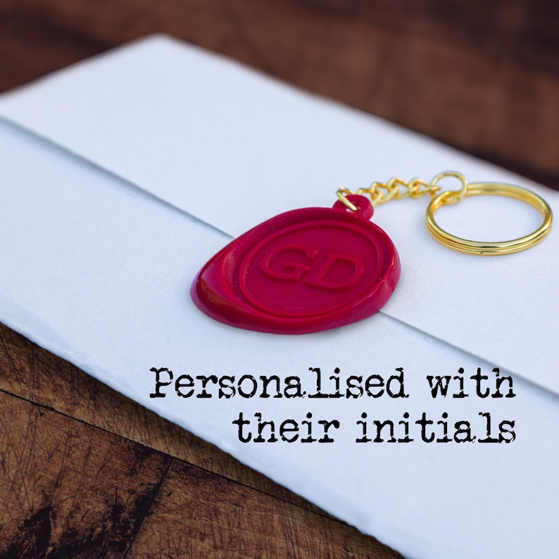 Red wax seal-style keyring on a folded task, with text 'Personalised with their initials'