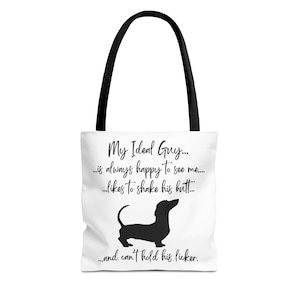 May include: White tote bag with black handles featuring a black silhouette of a dachshund and the text "My Ideal Guy... is always happy to see me... likes to shake his butt... and can't hold his licker."