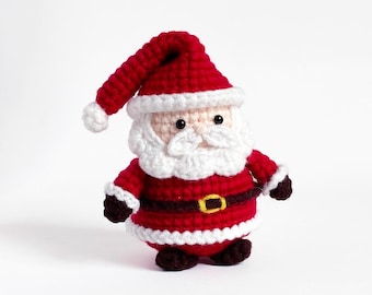Puede incluir: Un adorno de Papá Noel de crochet con un gorro rojo, barba blanca y botas marrones.