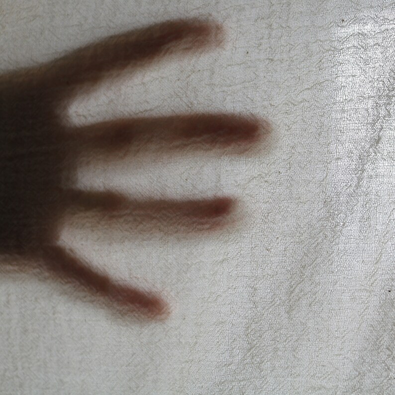 Puede incluir: Un primer plano de la sombra de una mano proyectada sobre una superficie blanca texturizada.