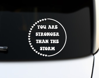 May include: White vinyl sticker with a circle of hearts around the text "You are stronger than the storm".