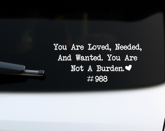 May include: White vinyl sticker on a black car with the text "You Are Loved, Needed, And Wanted. You Are Not A Burden." and the number "#988" below the text.