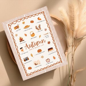 May include: A rectangular, cream-colored print with a brown border and a striped pattern. The print features the word "Autumn" and a "Family Bucket List" with fall-themed illustrations like pumpkins, leaves, and a bonfire.
