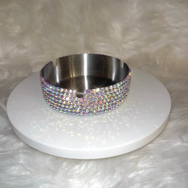 May include: A silver ashtray with a decorative iridescent crystal trim.
