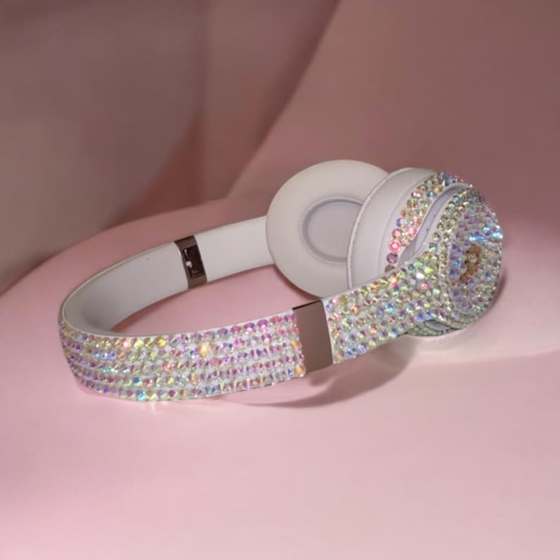 May include: White headphones with a crystal-like design. The headphones are covered in iridescent rhinestones.