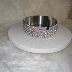 May include: A silver ashtray with a round, flat base and a rim decorated with iridescent rhinestones.