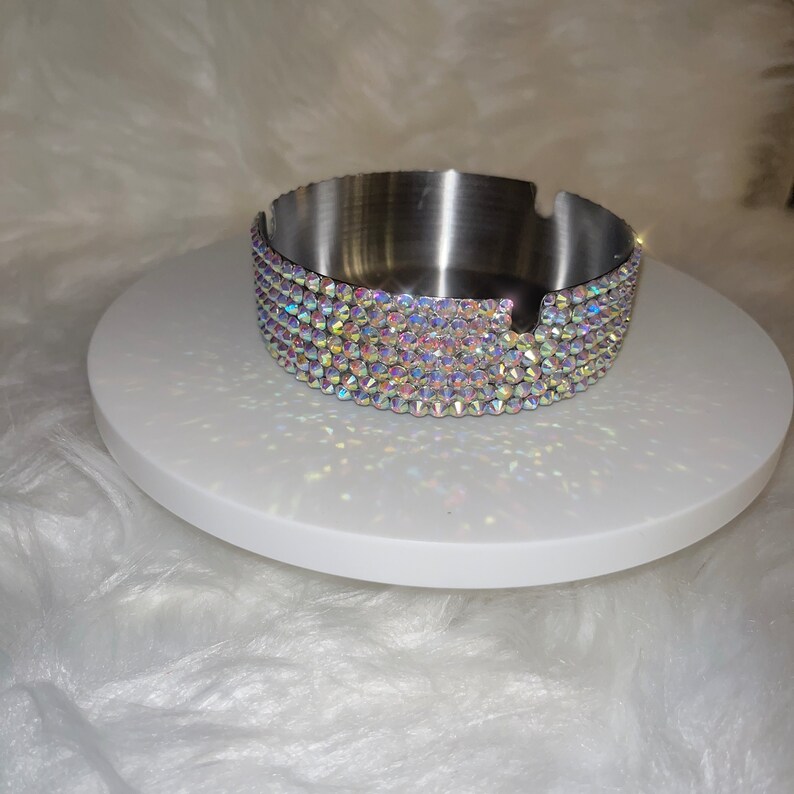 May include: A silver ashtray with a round, flat base and a rim decorated with iridescent rhinestones.