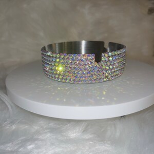 May include: A silver ashtray with a round, flat base and a rim decorated with iridescent rhinestones.