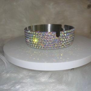 May include: A silver ashtray with a round, flat base and a rim decorated with iridescent rhinestones.
