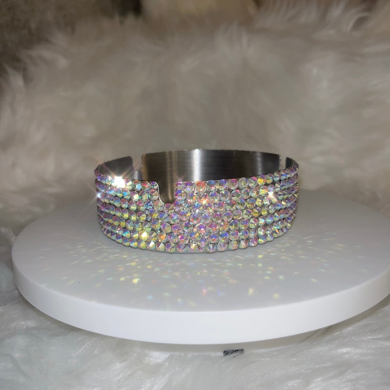 May include: A silver ashtray with a round, flat base and a rim decorated with iridescent rhinestones.