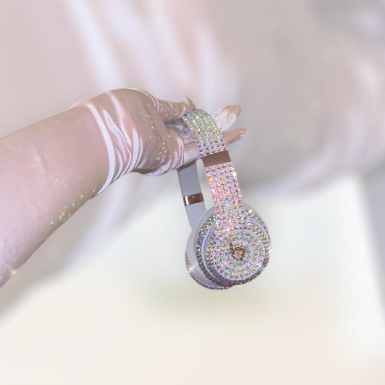 May include: White over-ear headphones with a crystal-like design. The headphones are covered in iridescent rhinestones.