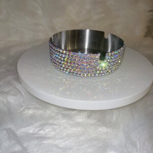 May include: A silver ashtray with a decorative band of iridescent rhinestones around the top edge.