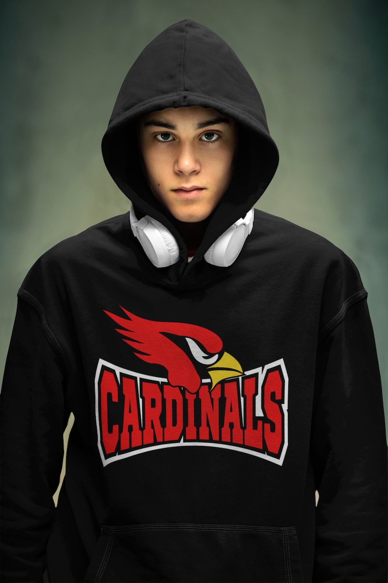 以下が含まれることがあります： 赤いカーディナルのロゴと白い文字で「CARDINALS」と書かれた黒いフード付きスウェットシャツ。首に白いヘッドホンをかけています。