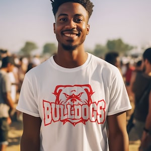 Op de afbeelding: Een wit T-shirt met een rode bulldog-afbeelding en het woord "BULLDOGS" in witte letters.