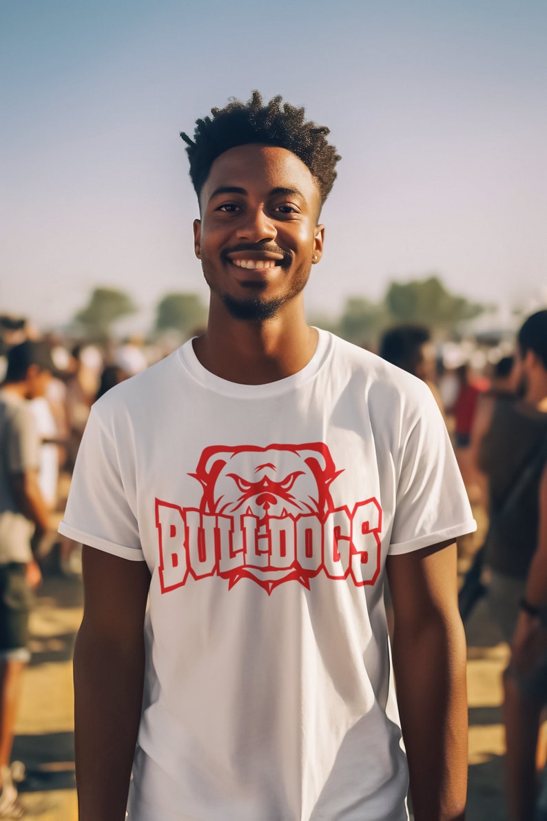 Op de afbeelding: Een wit T-shirt met een rode bulldog-afbeelding en het woord "BULLDOGS" in witte letters.