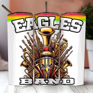 K&ouml;nnte beinhalten: Ein wei&szlig;er Becher mit einem bunten Design mit den Worten "Eagles Band" und einer Grafik von Musikinstrumenten, darunter Trompeten, eine Trommel und eine Tuba.