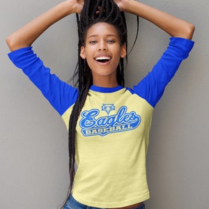 May include: A yellow and blue baseball t-shirt with the text "Eagles Baseball" and a blue eagle graphic. The shirt has a blue and yellow color block design.