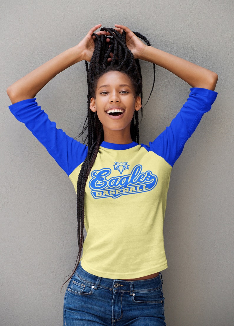 May include: A yellow and blue baseball t-shirt with the text "Eagles Baseball" and a blue eagle graphic. The shirt has a blue and yellow color block design.