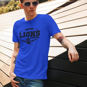 May include: A royal blue t-shirt with a black graphic of a lion's head inside a football. The text "LIONS FOOTBALL" is above the lion's head.