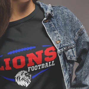 May include: A black t-shirt with a blue and red graphic of a football with the word "LIONS" in red and "FOOTBALL" in white.