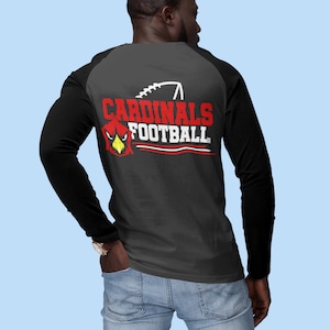 Puede incluir: Una camiseta de manga larga negra y gris con un dise&ntilde;o de estilo b&eacute;isbol en blanco y negro en la espalda. El dise&ntilde;o presenta una cabeza de cardenal roja con las palabras "CARDINALS FOOTBALL" en blanco.