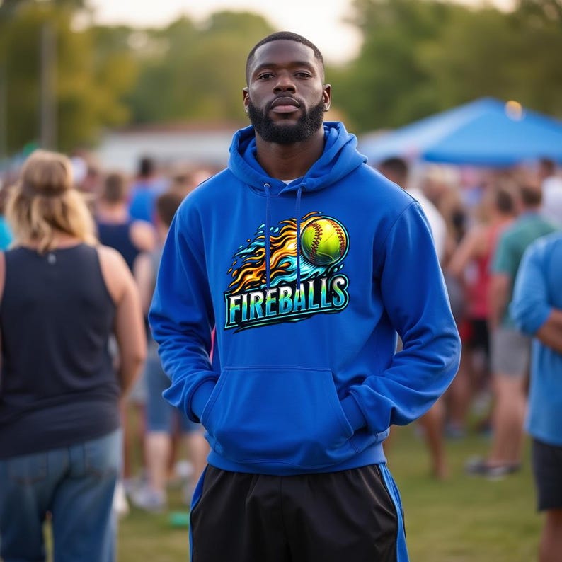 Puede incluir: Una sudadera con capucha azul real con un dise&ntilde;o de softbol con llamas y la palabra "FIREBALLS". La sudadera tiene capucha y bolsillo delantero. La persona lleva pantalones cortos negros.