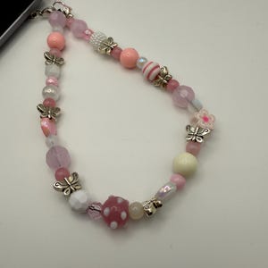 Rosa perlenbestickte Handytasche - silberne Perlen in Schmetterlingsform - rosa und weiße Perlen in verschiedenen Formen und Größen - schwarze Schnur - Handyarmband mit Schmetterlingsperlen