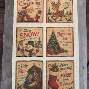 May include: A rectangular beige fabric panel featuring six distinct Christmas-themed illustrations. Each square includes festive imagery such as Santa Claus, a reindeer, a snowman, a decorated tree, a nativity scene, and a stocking with text.