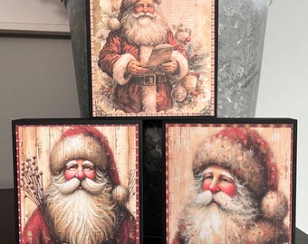 May include: Three wooden signs with images of Santa Claus. The top sign has the text "He knows if you've been bad or good." The other two signs feature close-up images of Santa's face.
