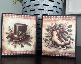 May include: Two framed Christmas-themed prints. One features a top hat adorned with holly and berries. The other showcases ice skates surrounded by holly and berries. Both prints have a vintage, rustic aesthetic with a red and white checkered border.