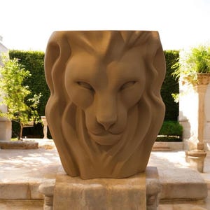 May include: A large, brown, stone sculpture of a lion's head. The sculpture is detailed and realistic, with a textured mane and a serious expression.
