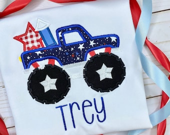 May include: White t-shirt featuring a patriotic monster truck design. The truck is navy blue with white stars and red accents, and has large black wheels with white star centers. The name "Trey" is embroidered in blue.