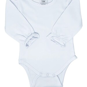 May include: White long-sleeved baby bodysuit with a round neckline and snap closures. The bodysuit has ruffled sleeves and shoulders. The label reads "AJ Blanks 3-6M 100% combed cotton Made in China."