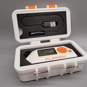 May include: A white and orange Flipper Zero multi-tool device with a digital screen and navigation buttons, housed in a white protective carrying case with black foam inserts. A black USB charging cable is included in the top foam compartment.