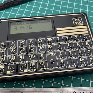 May include: A black and gold calculator with a digital display showing the number 3.1416. The calculator has a variety of buttons, including trigonometric functions, logarithms, and statistical calculations. The calculator is labeled "PX 11C".