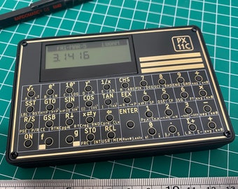 Könnte beinhalten: Ein schwarz-goldener Taschenrechner mit einem digitalen Display, das die Zahl 3.1416 anzeigt. Der Rechner verfügt über eine Vielzahl von Tasten, darunter trigonometrische Funktionen, Logarithmen und statistische Berechnungen. Der Rechner ist mit "PX 11C" beschriftet.