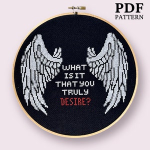 Pode incluir: Padrão de ponto cruz com um par de asas de anjo brancas sobre um fundo preto. O texto "What is it that you truly desire?" está escrito em branco com a palavra "desire" em vermelho.