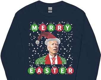 May include: A navy blue long-sleeved t-shirt with a Christmas-themed design featuring a man wearing a Santa hat and a green and red sweater. The text "Merry Easter" is printed in red and green letters with ornaments.