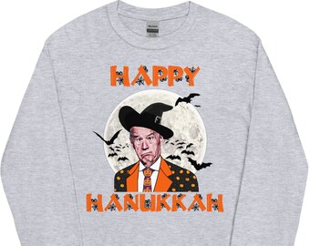 May include: A grey long-sleeved t-shirt with the text "Happy Hanukkah" in orange letters. A cartoon image of a man wearing a witch's hat and a suit with a tie is in front of a full moon with bats flying around it.