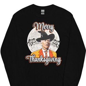 Puede incluir: Camiseta negra de manga larga con un gráfico de un hombre con un sombrero de bruja y el texto "Feliz Día de Acción de Gracias".