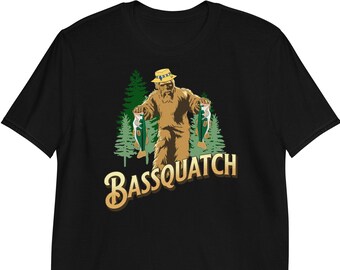 May include: Black t-shirt with a brown cartoon Bigfoot wearing a yellow hat and holding two green fish. The text "Bassquatch" is written in gold below the Bigfoot.
