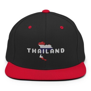 May include: Black and red baseball cap with an embroidered image of the country of Thailand and the word "THAILAND" in white lettering.