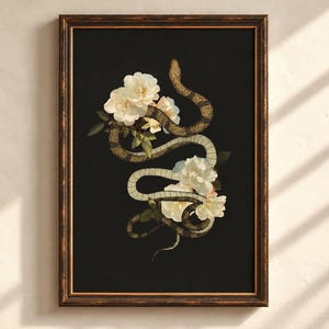 May include: A framed wall art print featuring a winding brown and tan snake intertwined with clusters of white flowers and green leaves against a solid black background, enclosed in a dark, textured wooden frame with gold trim.