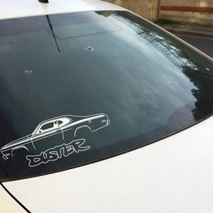 May include: A white silhouette of a classic car with the word "Duster" written underneath, on the rear window of a silver car.