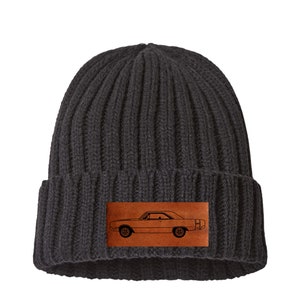 May include: A black knit beanie with a brown leather patch featuring a vintage car silhouette.